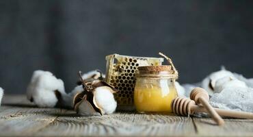 bomull honung i en glas flaska på en trä- yta. foto
