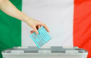 kvinna hand håller valsedel över valsedel låda. italiensk flagga i de bakgrund. foto