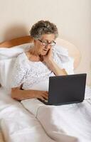 gammal kvinna är kommunicerar genom henne dator kvickhet släktingar foto