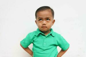 porträtt av en allvarlig asiatisk liten pojke vem utseende olycklig, isolerat på de vit bakgrund foto