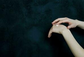 kvinna händer innehav och applicering fuktighetskräm. foto