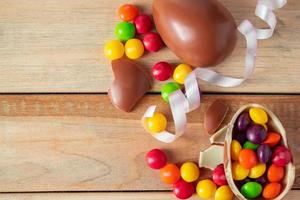 flerfärgade sötsaker och påskchokladägg på en ljus träbakgrund. foto