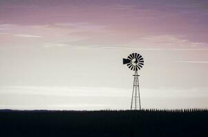 väderkvarn i landsbygden på solnedgång, pampas, patagonien, argentina. foto