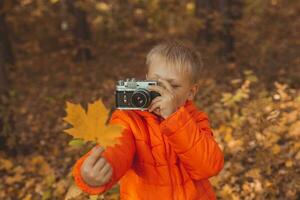 pojke med retro kamera tar bilder utomhus- i höst natur. fritid och fotografer begrepp foto