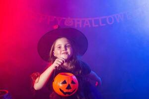 rolig barn flicka i häxa kostym för halloween med pumpa jack. foto