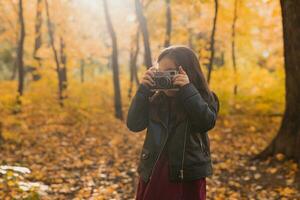 barn flicka använder sig av ett gammaldags kamera i höst natur. fotograf, falla säsong och fritid begrepp. foto