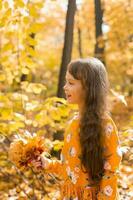 liten unge flicka med höst orange löv i en parkera. livsstil, falla säsong och barn begrepp. foto