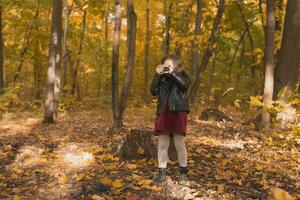 barn flicka använder sig av ett gammaldags kamera i höst natur. fotograf, falla säsong och fritid begrepp. foto