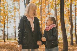 mormor med barnbarn i höst parkera. generation och familj begrepp. foto