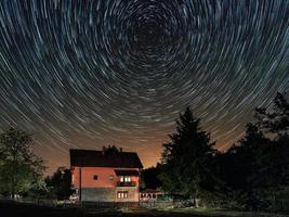 stjärnspår ovanför huset. bostadshus och stjärnspåren på himlen. natthimlen är astronomiskt korrekt. foto