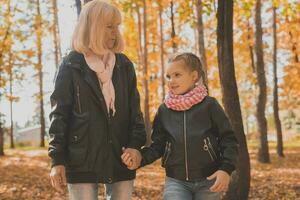 mormor med barnbarn i höst parkera. generation och familj begrepp. foto