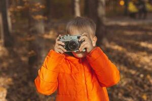 pojke med retro kamera tar bilder utomhus- i höst natur. fritid och fotografer begrepp foto