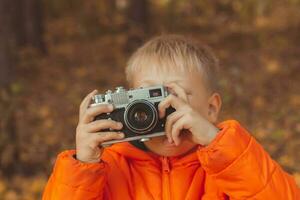 pojke med retro kamera tar bilder utomhus- i höst natur. fritid och fotografer begrepp foto