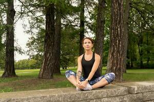 sport kvinnosport kvinna bär övning kostym håller på med stretching kondition övning i parkera foto