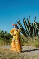 mexikansk kvinna i färgrik klänning och skalle smink i de mexikansk öken- kaktus foto