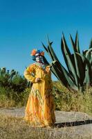 mexikansk kvinna i färgrik klänning och skalle smink i de mexikansk öken- kaktus foto