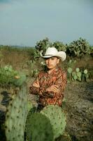 ung man med mexikansk hatt i en öken- landskap med kaktus foto