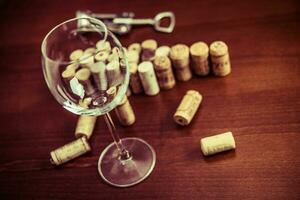 korkskruv, vin glas, och vin korkar på trä- tabell bakgrund foto