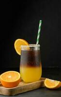 iced kaffe med orange juice i en transparent glas, uppfriskande stappla kaffe på de tabell foto