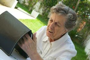 ett gammal kvinna är tittar på en läsplatta foto