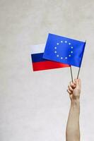 en hand med två flaggor - eu och ryssland foto