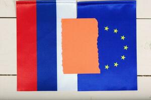 två flaggor av eu och ryssland på en vit trä- yta. topp se foto
