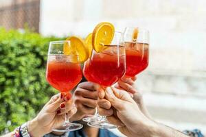 händer av grupp av vänner toasting en röd cocktail foto