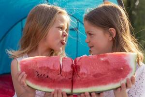 porträtt av två Söt liten systrar flickor är har roligt medan äter en skiva av vattenmelon foto