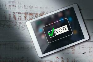 topp se av digital läsplatta på trä skrivbord med uppkopplad röstning på skärm. politisk begrepp. elektronisk internet röstning. kund respons. foto