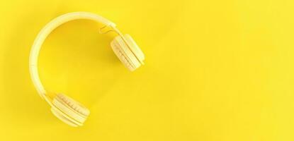 topp se av hörlurar på gul bakgrund. minimalistisk Foto av hörlurar med kopia Plats. gul dj hörlurar.