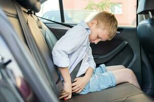 en pojke i shorts och en skjorta är Sammanträde i de bil och knäckning hans sittplats bälte. foto
