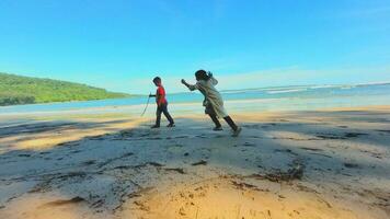 aceh, Indonesien, juli 7, 2023. två barn spelar, turister på en sandig strand i de svart hav på de strand i sommar foto