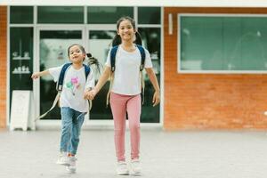 två liten flickor med ryggsäckar och ryggsäckar i de skola. foto
