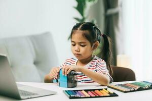 asiatisk liten barn flicka teckning med Färg pennor i levande rum på Hem foto