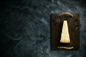 topp se av triangel- bit av hård ost på trä- skärande styrelse foto