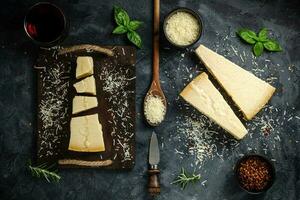 bit av parmesan ost och ost kniv. på en mörk bakgrund. traditionell italiensk ost. topp se. copy foto