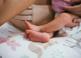 nyfödd bebis fötter på vit filt. mor håll fötter av nyfödd bebis. maternity och barndom begrepp. foto