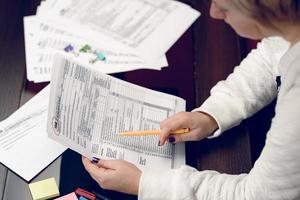 kvinnan fyller i skatteformuläret och arbetar med skattedokument. blankett 1040 individuell inkomstdeklarationsblankett. USA: s skatteformulär. amerikanska blanketter. skattetid. foto