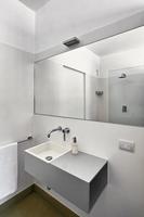 modernt badrumsinredning i förgrunden tvättstället med en stor spegel foto