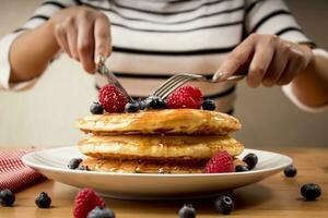 ung kvinna äter pannkakor i de morgon- - frukost varma kakor foto