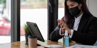 ung affärskvinna som bär ansiktsmask medan hon arbetar på en dator på kontoret foto