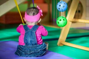 skön tio månader bebis flicka spelar med färgrik bollar. tidigt stimulering för småbarn begrepp. foto