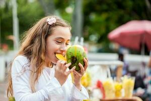 skön ung flicka på paseo bolivar fyrkant i de stad av cali äter tropisk frukt i colombia foto