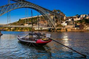 skön traditionell båt och de dom luis jag bro en metall båge bro över de douro flod mellan de städer av porto och vila nova de gaia i portugal invigt i 1886 foto