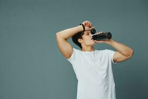 övning man sport flaska kille vatten dryck t-shirt passa isolerat sportsman foto