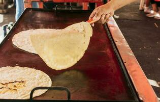 traditionell handgjort nikaraguanska tortillas, traditionell handgjort majs tortillas på de grill. händer framställning traditionell tortillas på grill, stänga upp av händer vända tortillas på grill foto