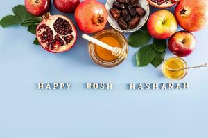 festlig bakgrund för rosh hashanah. en uppsättning av traditionell mat på en blå bakgrund med och trä- brev med de text av grattis. foto