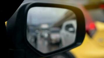 abstrakt vinge spegel se av bil. ser tillbaka för drving i de stad kan ser suddig av gul bil. foto