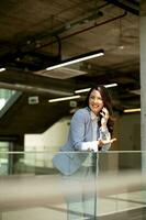 ung företag kvinna använder sig av mobil telefon i de kontor hall foto