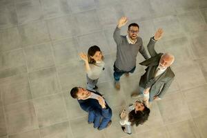 antenn se på Lycklig företag människor höja händer tillsammans med glädje och Framgång i de kontor hall foto